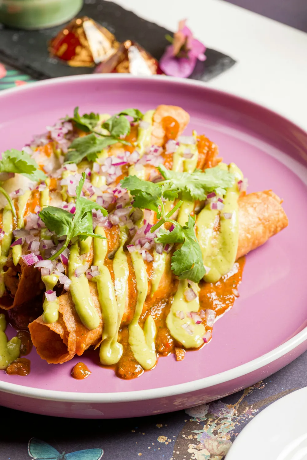 Enchiladas topped with avocado sauce and onion